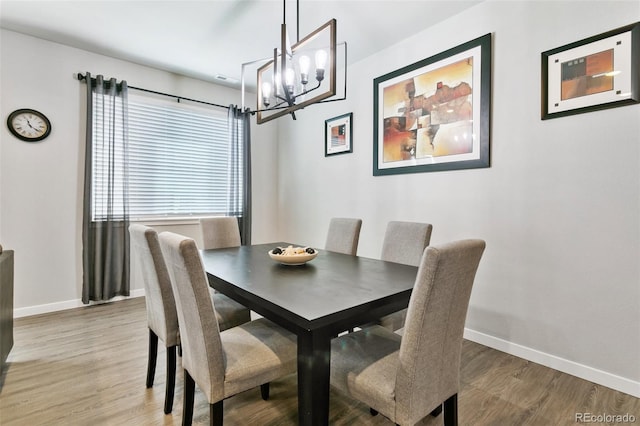 dining space featuring light wood finished floors, a chandelier, and baseboards