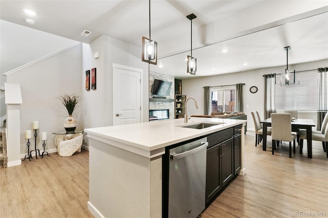 kitchen with a sink, light wood-style flooring, open floor plan, and stainless steel dishwasher