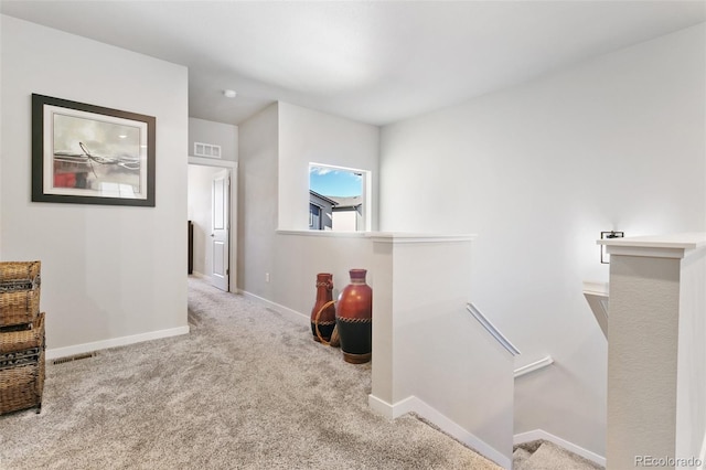 hall featuring visible vents, carpet flooring, an upstairs landing, and baseboards