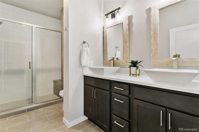 bathroom with double vanity, toilet, a stall shower, and a sink