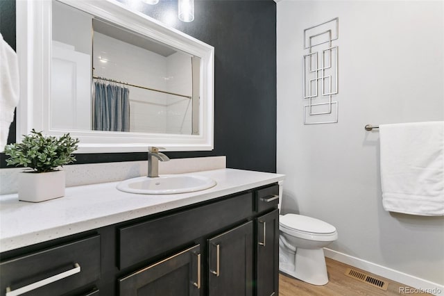 full bathroom featuring visible vents, baseboards, toilet, wood finished floors, and vanity