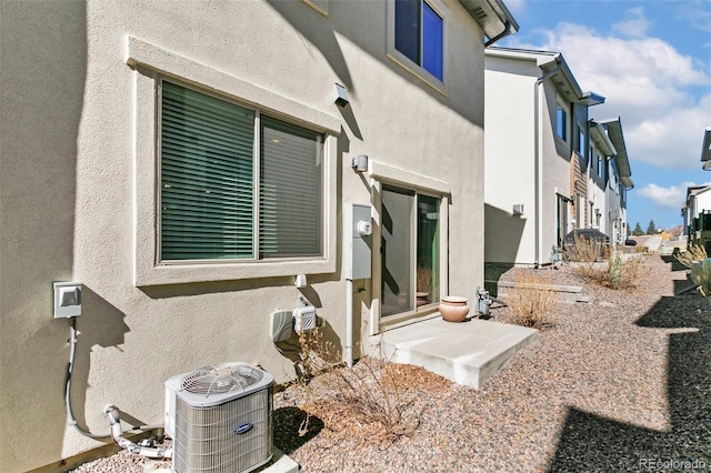 doorway to property featuring central AC and stucco siding