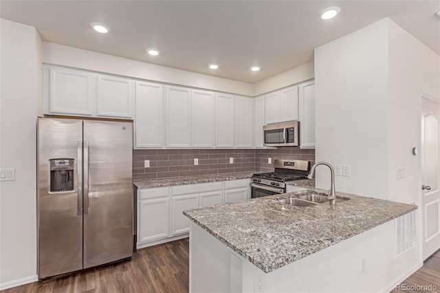 14065 Harrison St, Thornton, CO 80602 - kitchen with stainless steel appliances, dark wood-style flooring, light stone countertops, a peninsula, and white cabinets