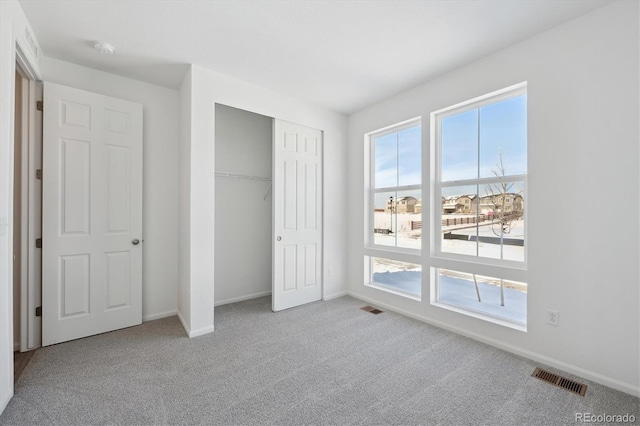 unfurnished bedroom featuring a closet and light colored carpet