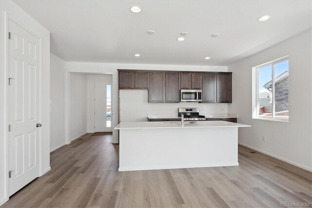 kitchen with a center island with sink, appliances with stainless steel finishes, and dark brown cabinetry