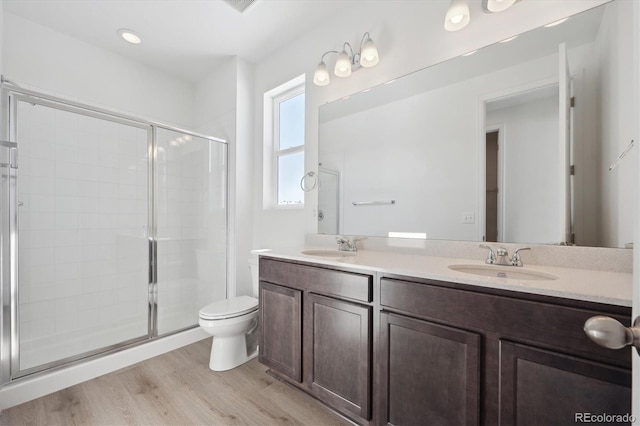 bathroom with vanity, a shower with door, toilet, and hardwood / wood-style floors