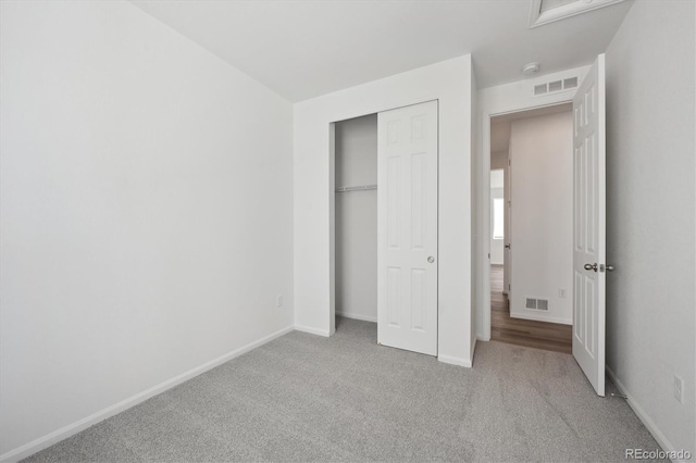 unfurnished bedroom featuring a closet and light colored carpet