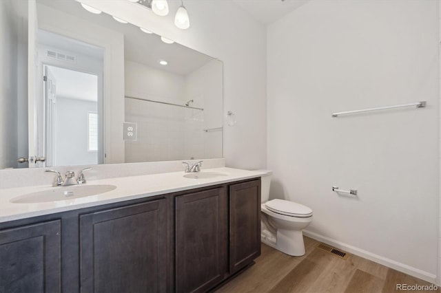 bathroom featuring toilet, hardwood / wood-style flooring, a shower, and vanity