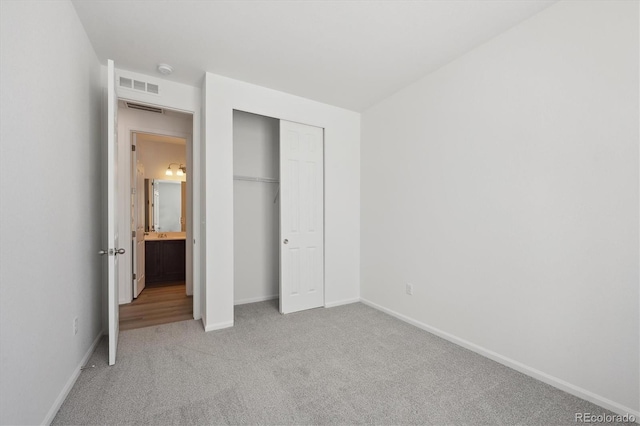 unfurnished bedroom with light carpet and a closet