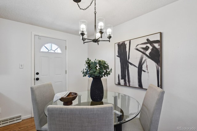 dining area with an inviting chandelier, dark hardwood / wood-style floors, and a textured ceiling