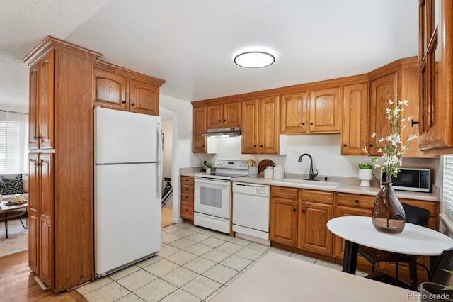 kitchen with white appliances, sink, a textured ceiling, and light tile patterned floors