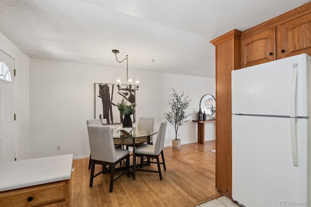 dining room with a notable chandelier, light hardwood / wood-style floors, and a textured ceiling