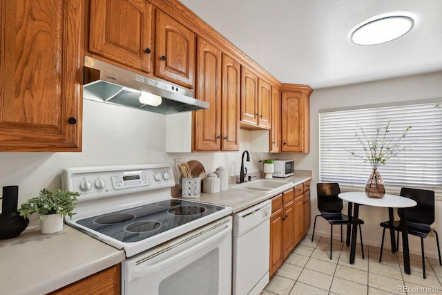 kitchen featuring light tile patterned flooring, white appliances, and sink