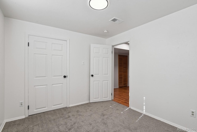 unfurnished bedroom featuring light carpet and a closet