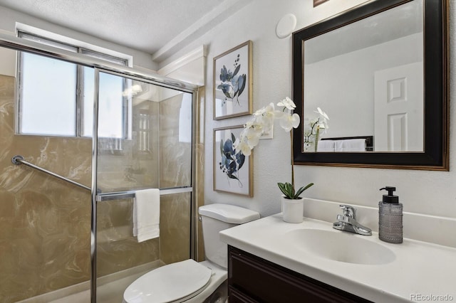 bathroom featuring vanity, toilet, a shower with shower door, and a textured ceiling