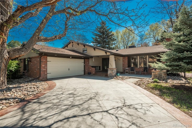 single story home with brick siding, a porch, an attached garage, and concrete driveway