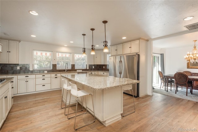 kitchen featuring stainless steel appliances, a kitchen island, tasteful backsplash, light stone countertops, and recessed lighting