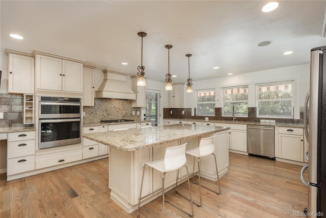 kitchen with appliances with stainless steel finishes, custom range hood, tasteful backsplash, light wood-type flooring, and recessed lighting