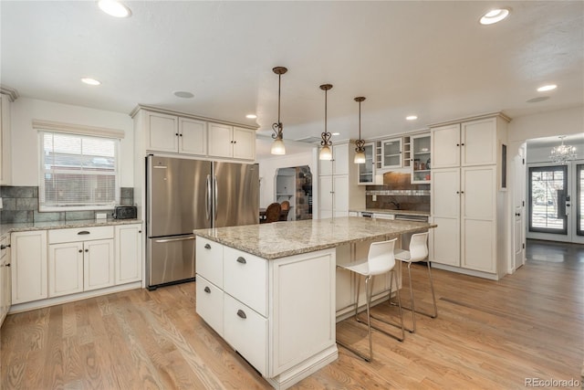 kitchen featuring freestanding refrigerator, tasteful backsplash, light wood finished floors, a kitchen island, and recessed lighting