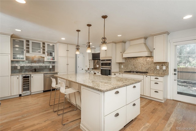 kitchen featuring custom range hood, beverage cooler, appliances with stainless steel finishes, backsplash, and light wood-type flooring