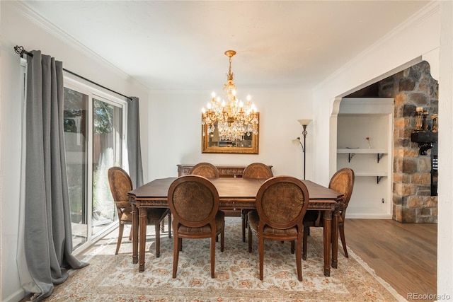 dining room with ornamental molding, light wood-style floors, a chandelier, and built in shelves