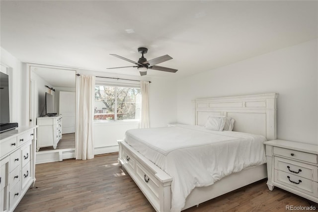 bedroom with wood finished floors, ceiling fan, a baseboard radiator, and baseboard heating