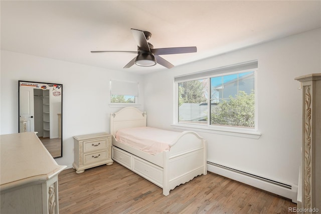 bedroom with a baseboard radiator, multiple windows, light wood-style flooring, and ceiling fan