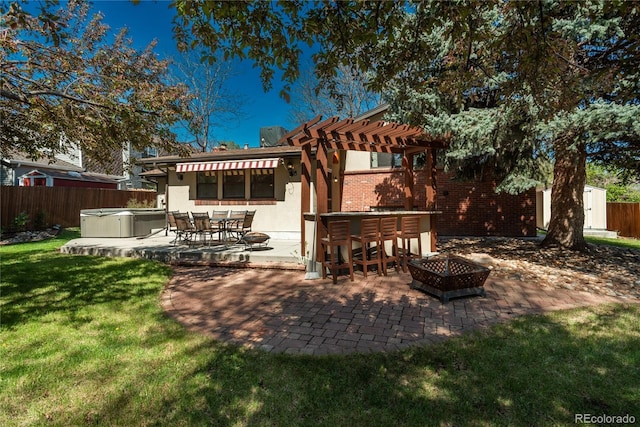 rear view of property with a hot tub, a patio, brick siding, a pergola, and a fire pit