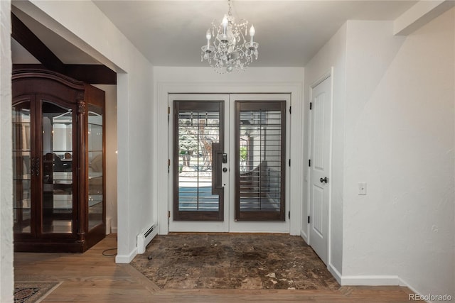 entryway with a baseboard heating unit, baseboards, a chandelier, and wood finished floors