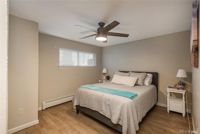 bedroom with a baseboard radiator, wood finished floors, and baseboards