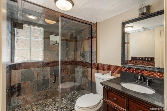 bathroom with tile walls, a stall shower, toilet, vanity, and decorative backsplash