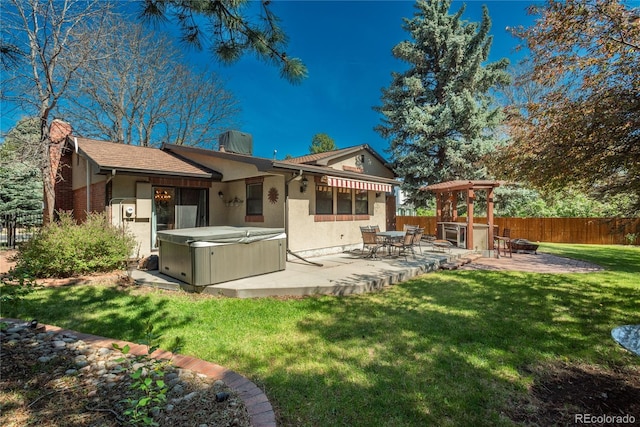 rear view of property featuring a hot tub, a patio area, a chimney, and stucco siding