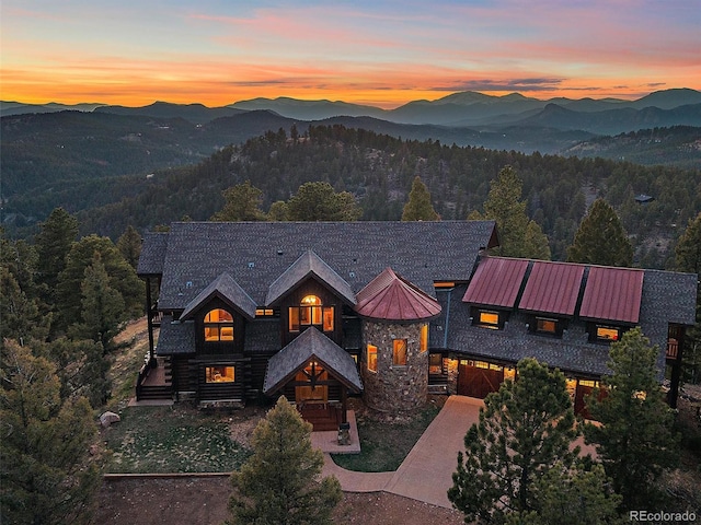29548 Sunset Trl, Pine, CO 80470 - view of front of house with a standing seam roof, a mountain view, stone siding, a garage, and a forest view
