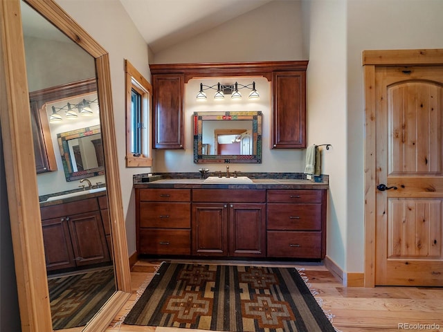 29548 Sunset Trl, Pine, CO 80470 - bathroom featuring vaulted ceiling, wood finished floors, a sink, baseboards, and two vanities