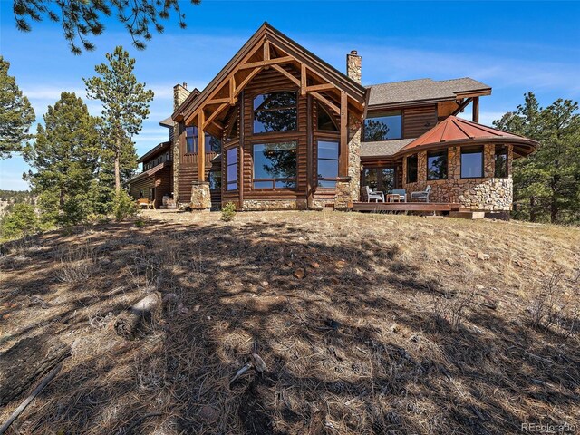29548 Sunset Trl, Pine, CO 80470 - back of house featuring a wooden deck, stone siding, a chimney, and a shingled roof