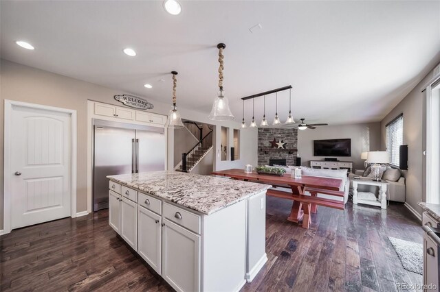 kitchen with dark hardwood / wood-style flooring, white cabinetry, light stone counters, built in refrigerator, and a center island