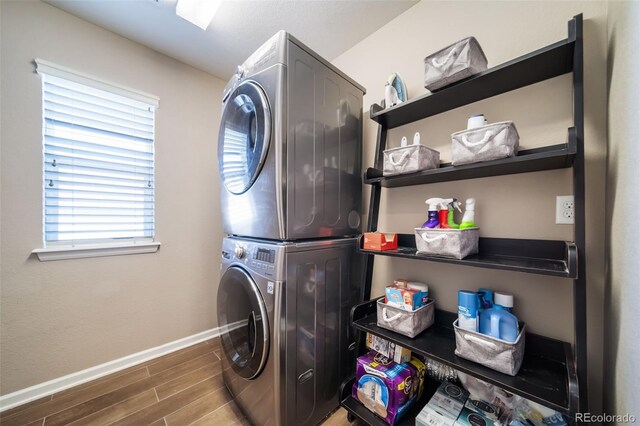 laundry area featuring dark wood-type flooring, a wealth of natural light, and stacked washing maching and dryer