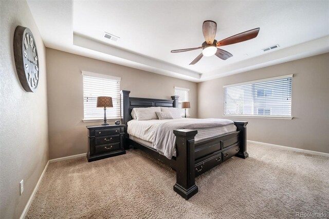 bedroom featuring ceiling fan, a raised ceiling, and carpet floors