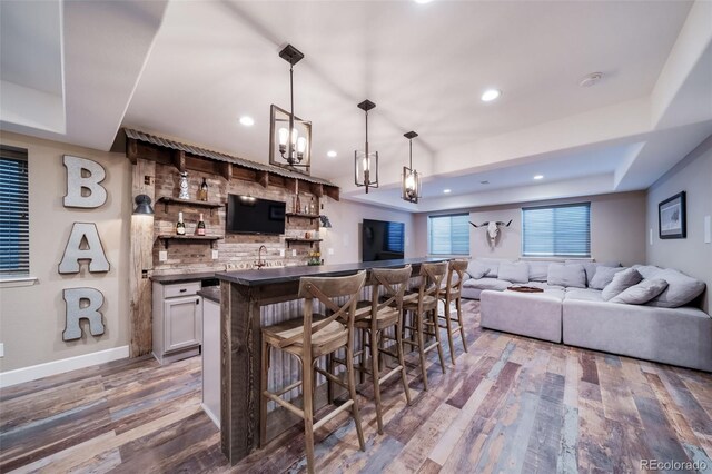 bar featuring white cabinets, a raised ceiling, pendant lighting, and wood-type flooring