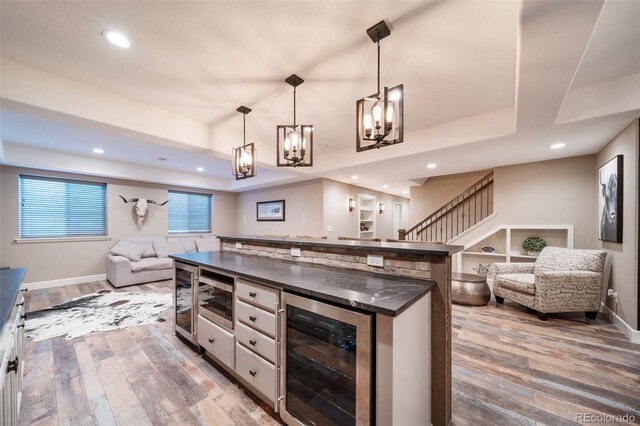 kitchen featuring wood-type flooring, wine cooler, hanging light fixtures, white cabinets, and a tray ceiling