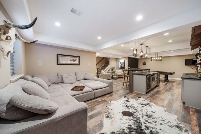 living room with bar, dark hardwood / wood-style floors, and a raised ceiling