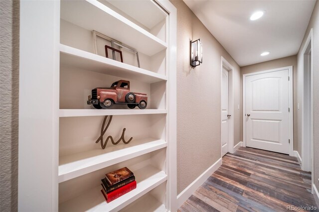 hallway with built in shelves and dark hardwood / wood-style flooring