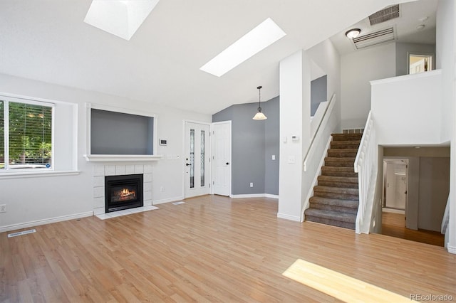 4947 S Espana Way, Centennial, CO 80015 - unfurnished living room featuring a skylight, stairway, a tile fireplace, light wood finished floors, and high vaulted ceiling