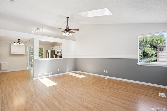 4947 S Espana Way, Centennial, CO 80015 - empty room featuring lofted ceiling, light wood finished floors, a ceiling fan, a skylight, and a chandelier