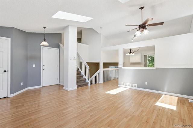 4947 S Espana Way, Centennial, CO 80015 - unfurnished living room featuring light wood-style floors, a skylight, lofted ceiling, ceiling fan, and stairs