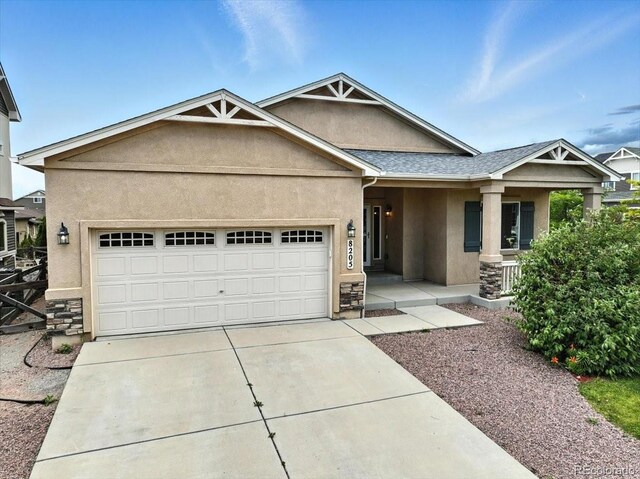 8205 Birch Tree Loop, Colorado Springs, CO 80927 - view of front of house featuring stucco siding, an attached garage, driveway, and a porch