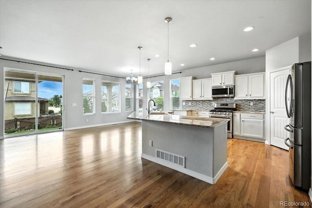 8205 Birch Tree Loop, Colorado Springs, CO 80927 - kitchen with stainless steel appliances, decorative backsplash, recessed lighting, light wood finished floors, and an island with sink