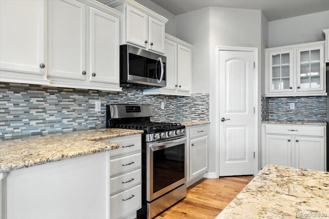8205 Birch Tree Loop, Colorado Springs, CO 80927 - kitchen featuring stainless steel appliances, white cabinets, decorative backsplash, light wood-type flooring, and glass insert cabinets