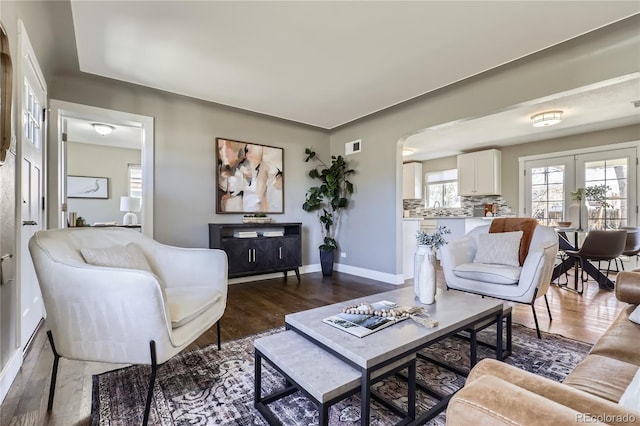 living room featuring dark wood-style floors, french doors, arched walkways, and baseboards