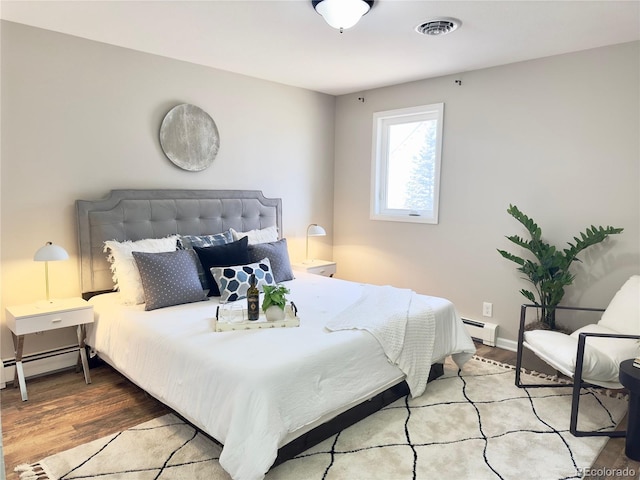 bedroom with baseboard heating and light hardwood / wood-style flooring